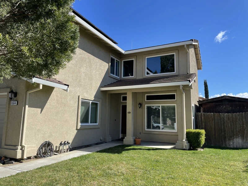 Exterior view of a two-story stucco home with newly replaced windows in Livermore by Landmark Exteriors.